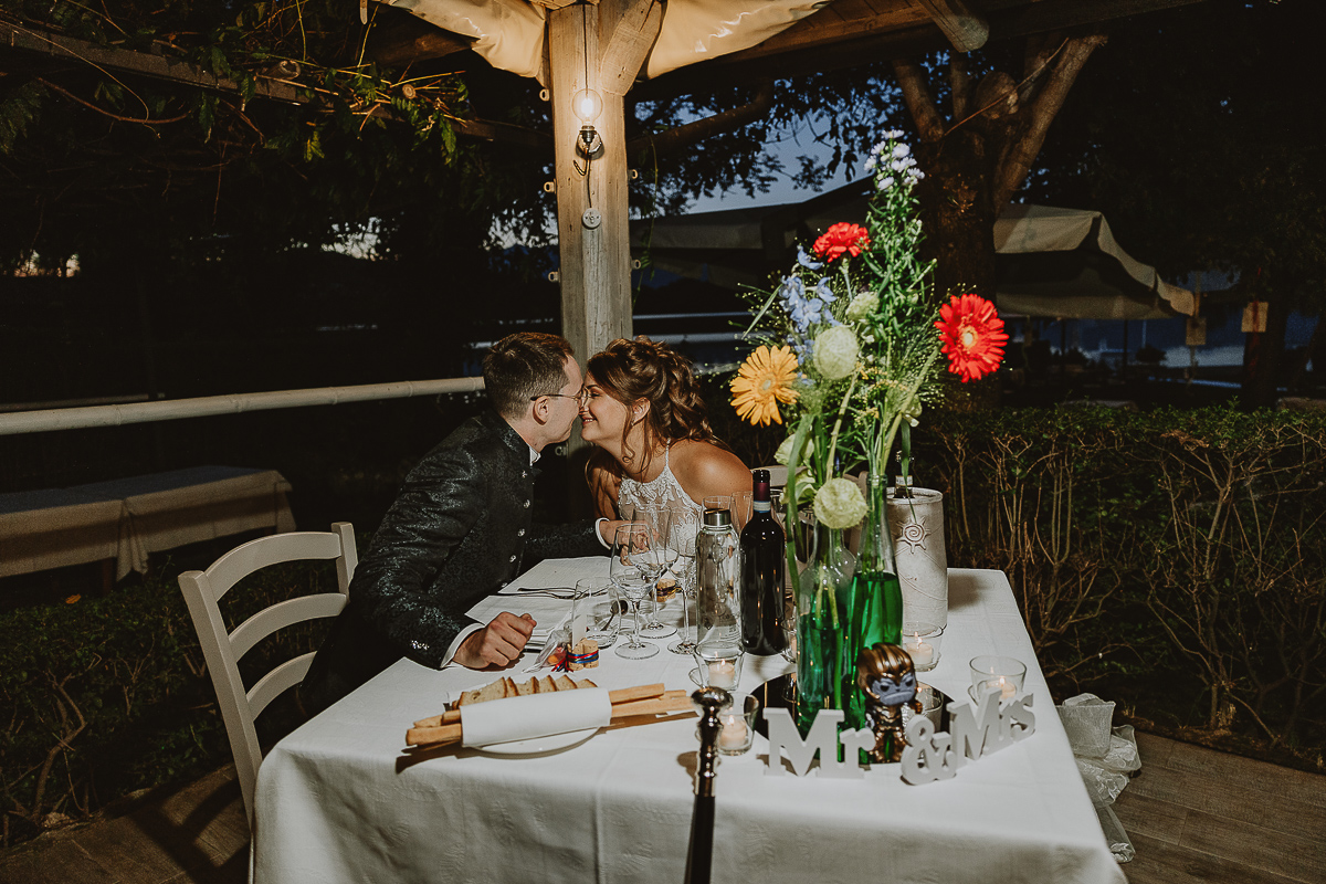 Matrimonio Lago di Candia. Ricevimento. Cena. Sposi al tavolo che si guardano.