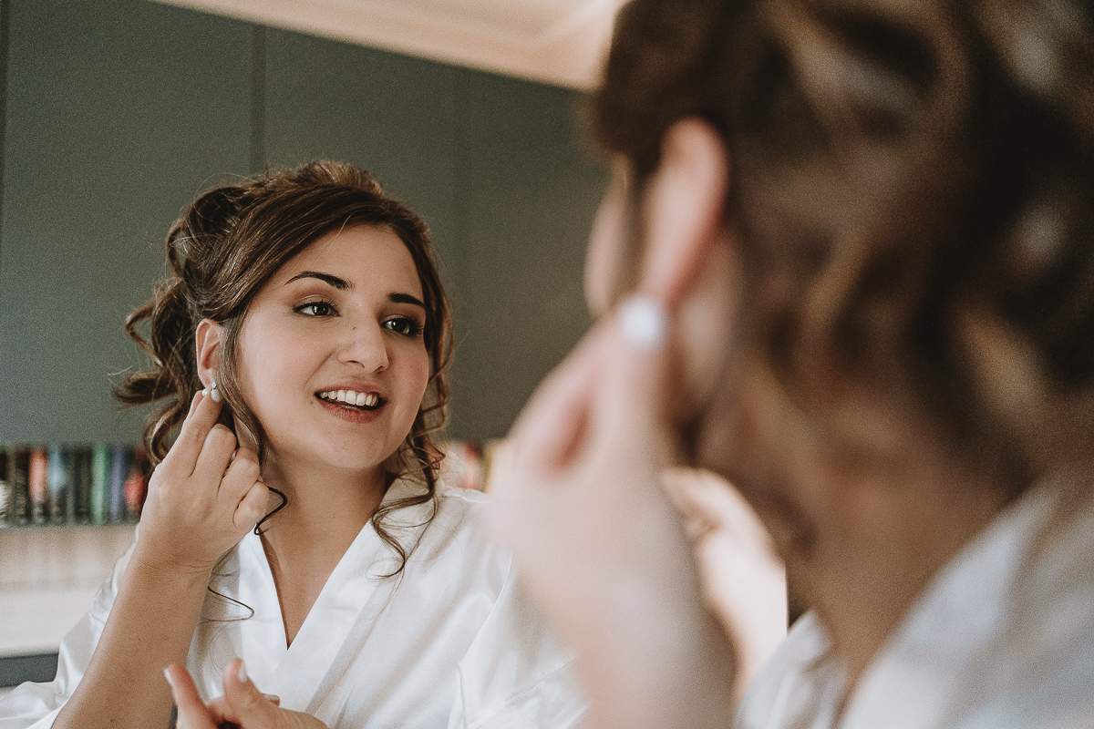 Matrimonio Lago di Candia . Preparazione della sposa. Sposa si mette gli orecchini.