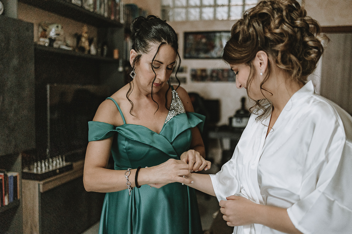 Matrimonio Lago di Candia . Preparazione della sposa. mamma aiuta la sposa ad indossare il braccialetto.