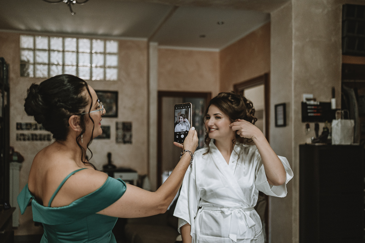 Matrimonio Lago di Candia . Preparazione della sposa. mamma scatta una foto con il telefono alla sposa.