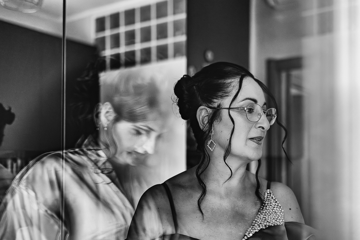 Matrimonio Lago di Candia . Preparazione della sposa. Ritratto della mamma con sposa riflessa nel vetro della finestra dietro di lei. Bianco enero.