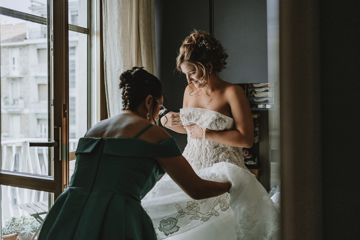 Matrimonio Lago di Candia . Preparazione della sposa. mamma aiuta la sposa ad indossare l'abito.