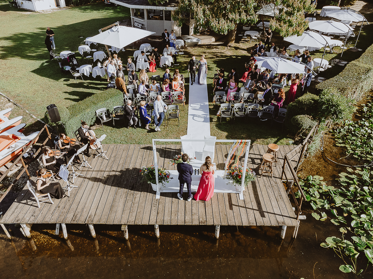 Matrimonio Lago di Candia. Cerimonia. Sposo e madre camminano verso l'altare guardandosi. Foto dal drone.
