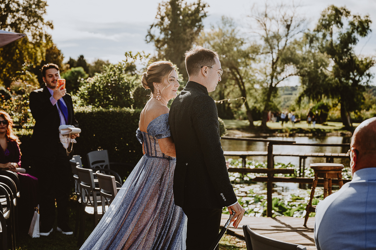 Matrimonio Lago di Candia. Cerimonia. Sposo e madre camminano verso l'altare guardandosi.