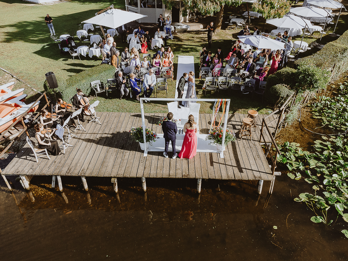 Matrimonio Lago di Candia. Cerimonia. Sposo e madre camminano verso l'altare guardandosi. Foto dal drone.