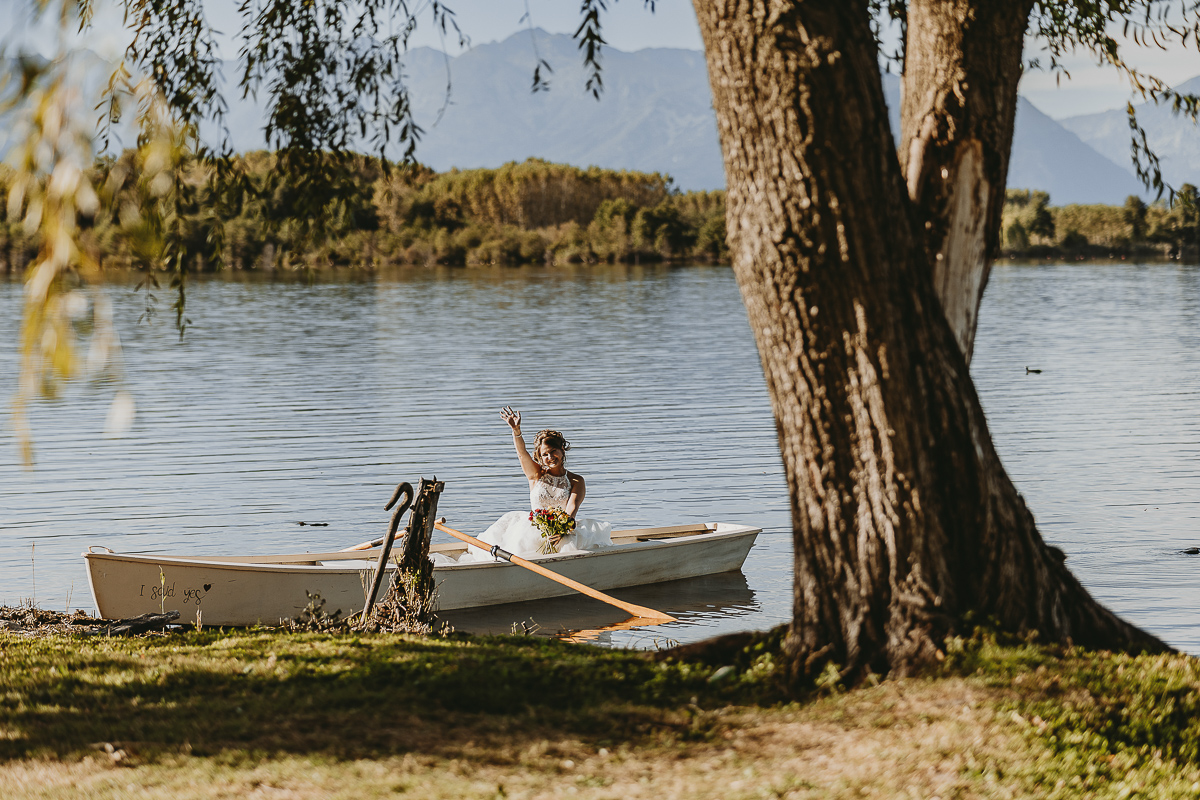 Matrimonio Lago di Candia. Cerimonia. Sposa sulla barca a remi saluta.