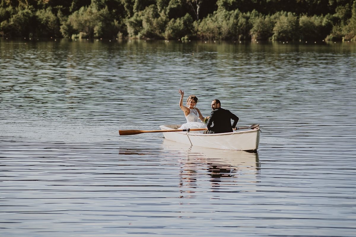 Matrimonio Lago di Candia. Cerimonia. Sposa sulla barca a remi saluta.