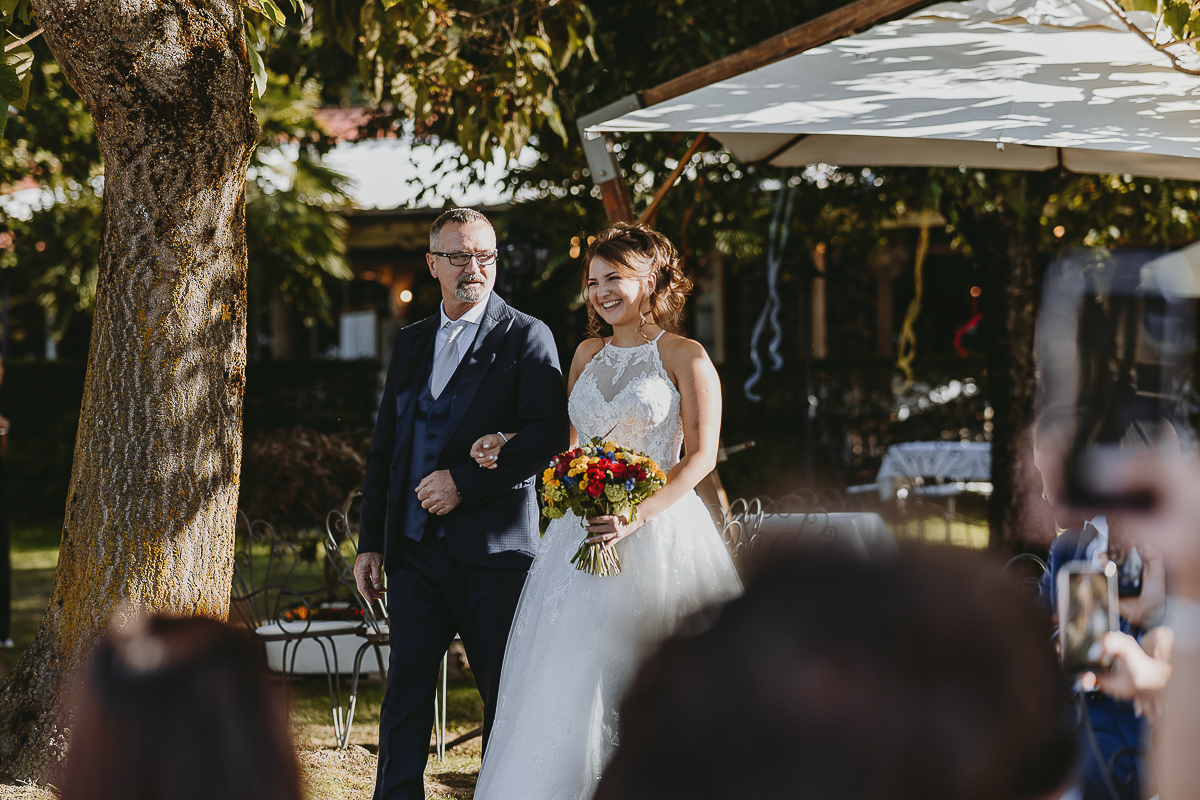 Matrimonio Lago di Candia. Cerimonia. Sposa a braccetto con il padre.