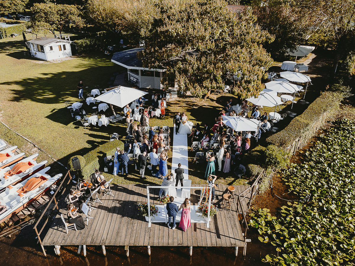 Matrimonio Lago di Candia. Cerimonia. Sposa fa l'ingresso nel luogo della cerimonia sul molo mentre lo sposo aspetta. foto panoramica dal drone.