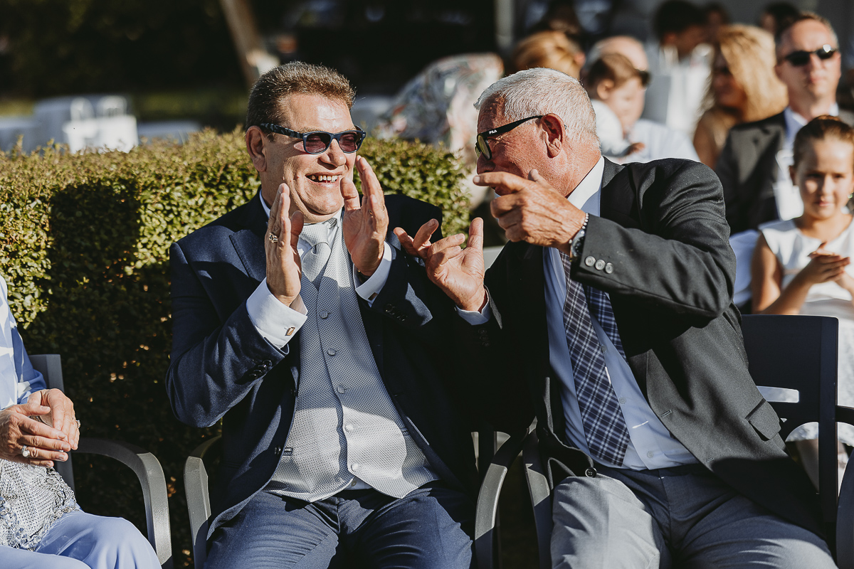 Matrimonio Lago di Candia. Cerimonia. padre e nonno dello sposo che ridono.