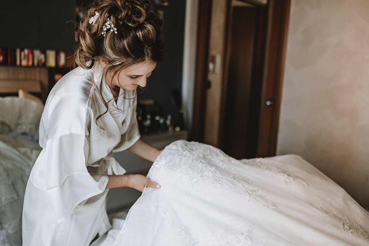 Matrimonio Lago di Candia . Preparazione della sposa. Sposa accarezza il suo vestito.