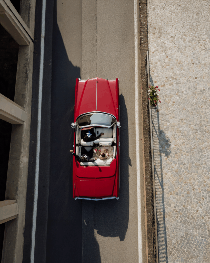 皮埃蒙特婚礼摄影师 – 乘坐闪亮复古红色凯迪拉克的新人的航拍照片