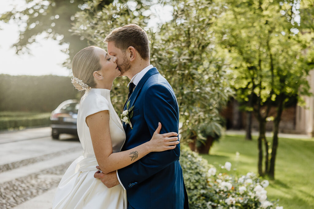 都灵婚礼摄影师，Villa Bria 的豪华婚礼。优雅的婚礼，新娘温柔而浪漫地亲吻新郎的脸颊。 