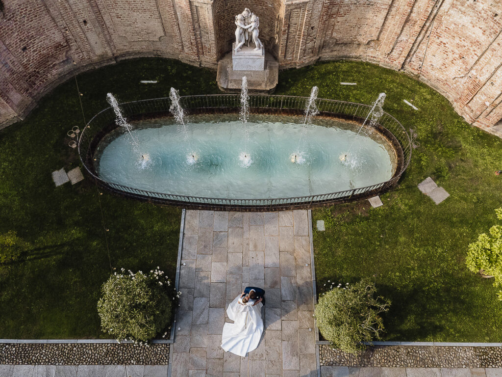 都灵婚礼摄影师 – Villa Bria 的豪华婚礼 – 航拍中新人在喷泉前亲吻