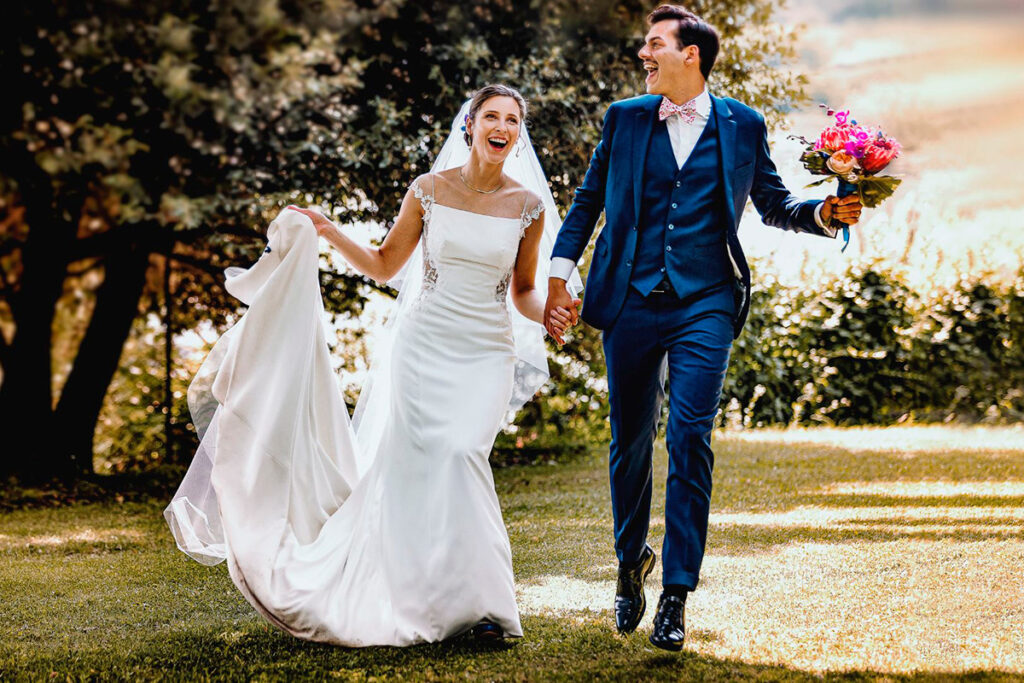 Scegliere il fotografo di matrimonio - sposi felici che ridono e corrono mano nella mano durante il loro giorno speciale"