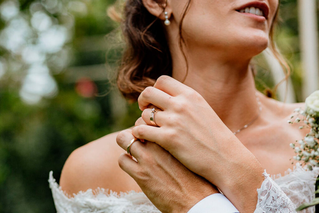 Scegliere il fotografo di matrimonio - dettagli emozionali delle mani degli sposi con le fedi nuziali"