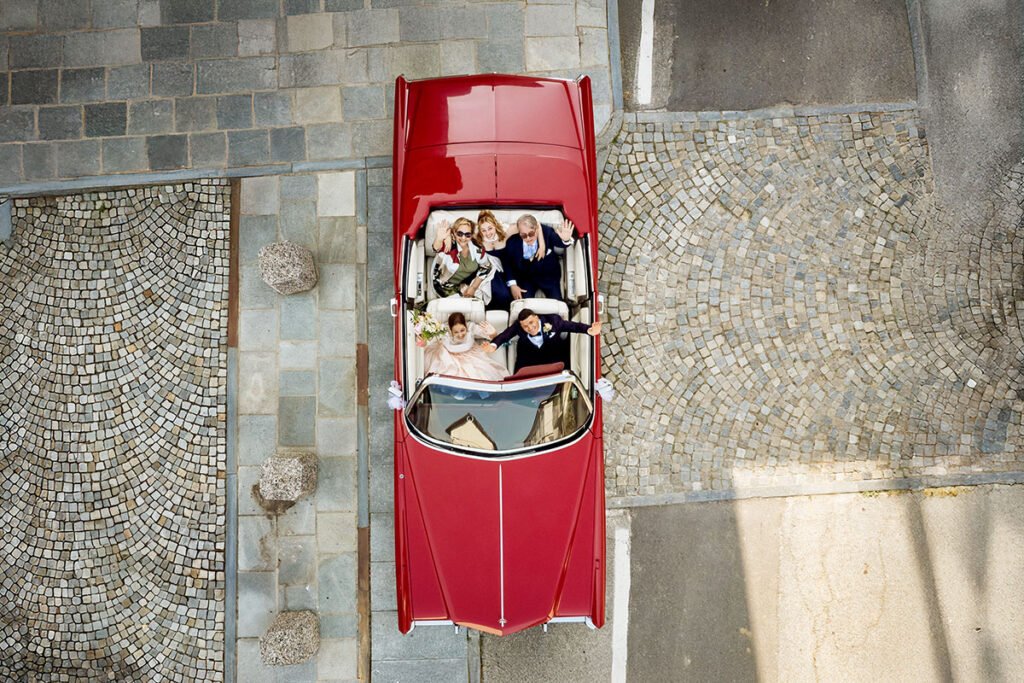 Scegliere il fotografo di matrimonio - foto di famiglia in auto Cadillac vintage rossa scattata dall’alto