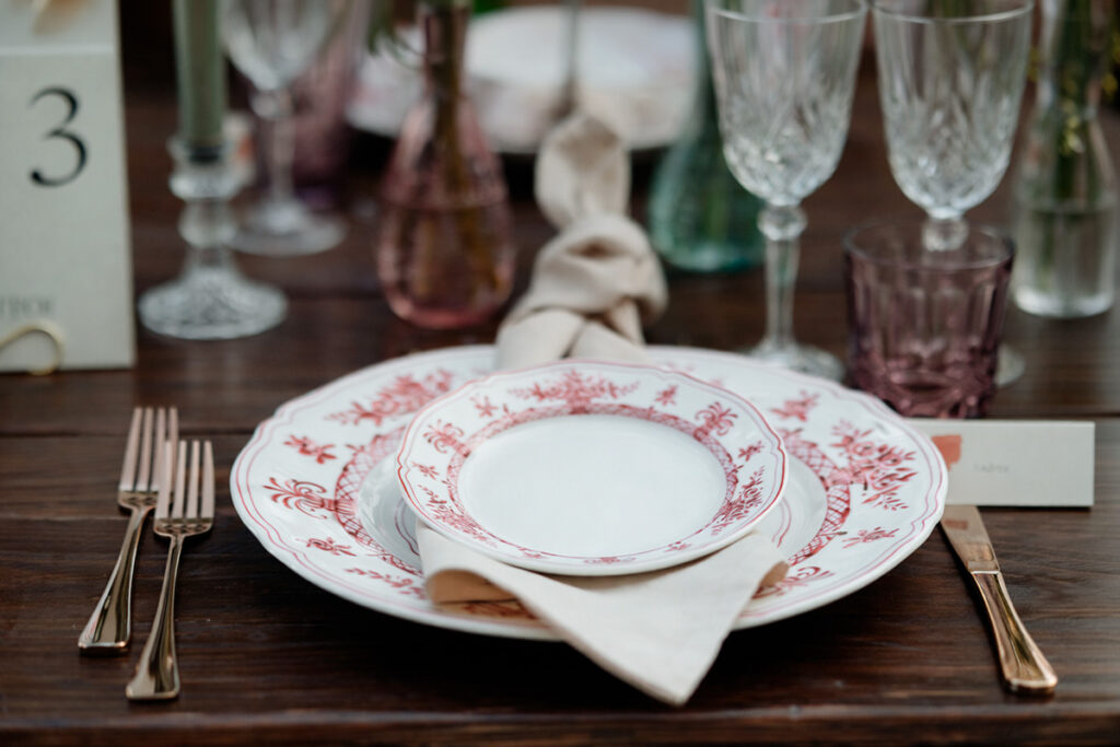 Dettaglio della mise en place di un matrimonio alla Cedrina con piatti decorati, tovagliolo in lino e bicchieri di cristallo e colorati
