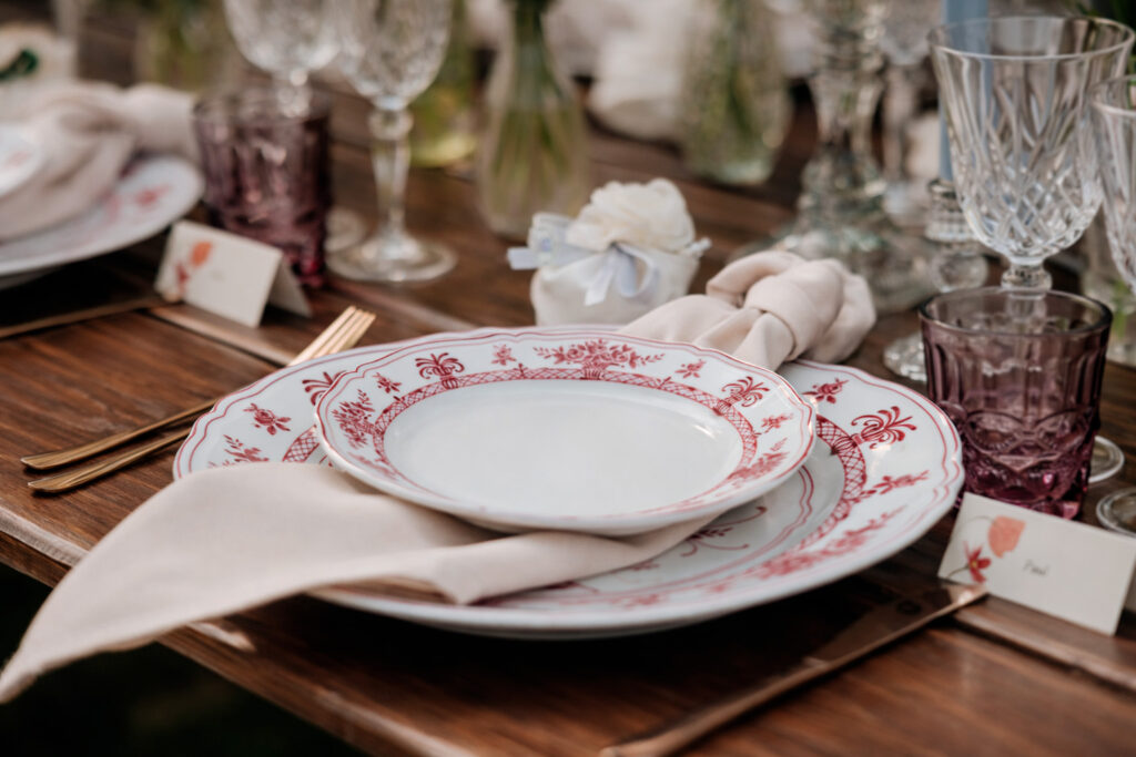 Dettaglio della mise en place di un matrimonio alla Cedrina con piatti decorati, tovagliolo in lino e tavolo in legno