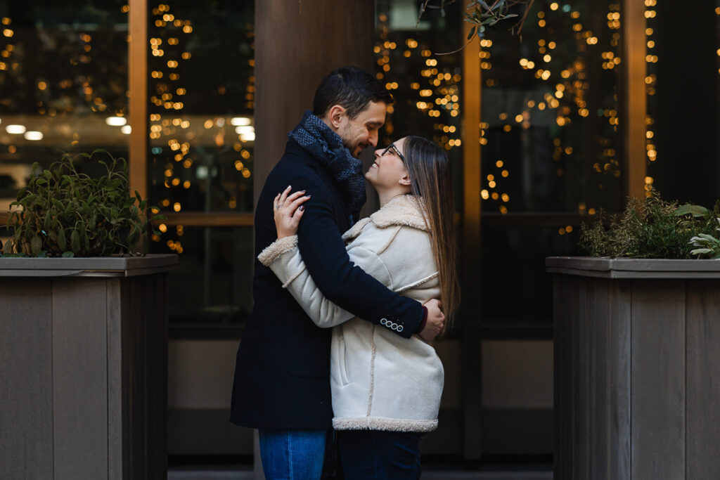 coppia sorridente di sera davanti alle lucine natalizie durante il pre-wedding a Torino